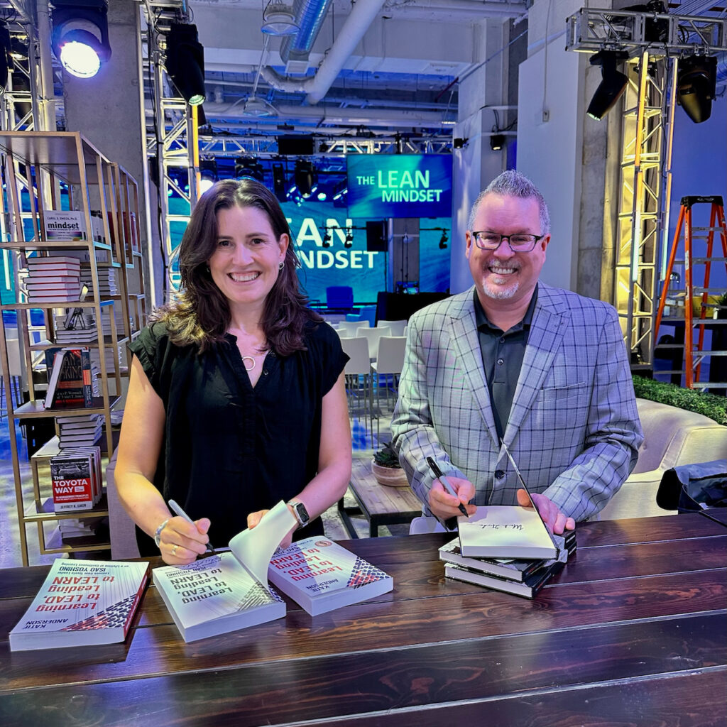 Katie Anderson and Mark Graban sign copies of their books.